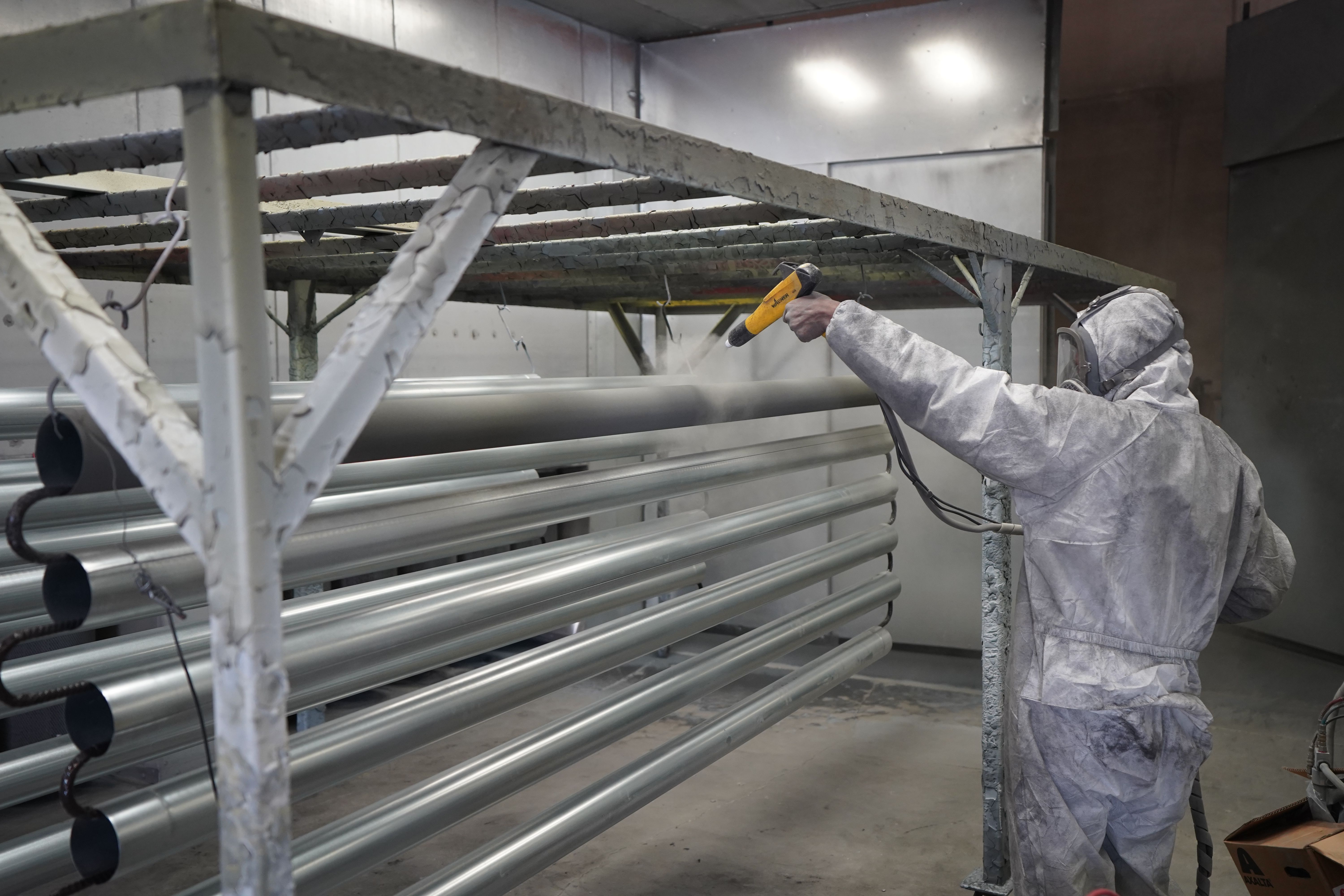 Large architectural metal pipe components being coated