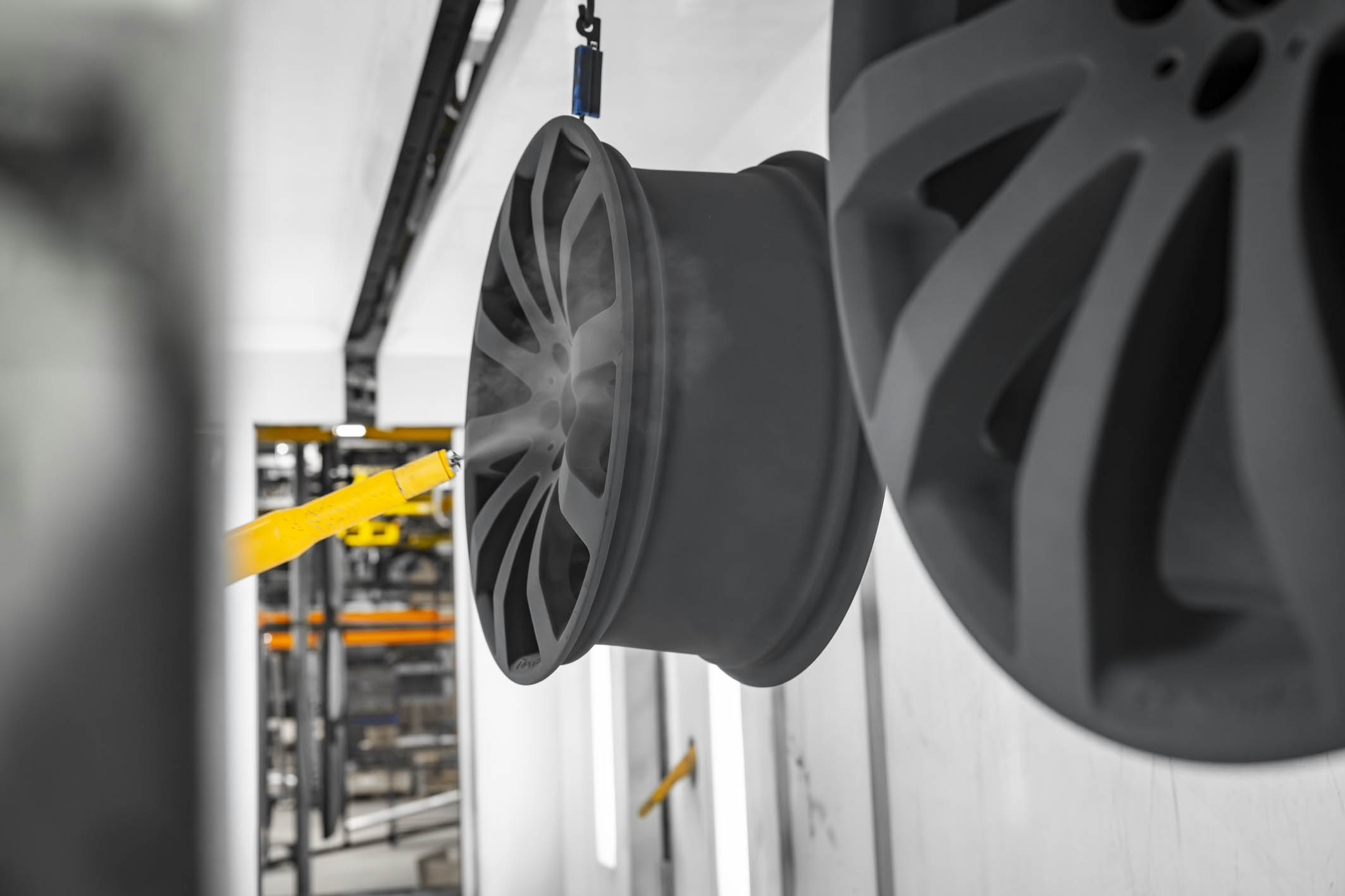 Automotive wheel rims moving through a powder coating surface finishing process